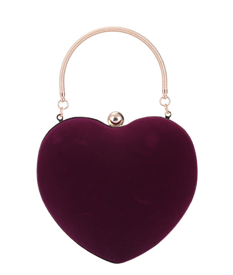 Heart-shaped purple handbag with a gold handle on a white background