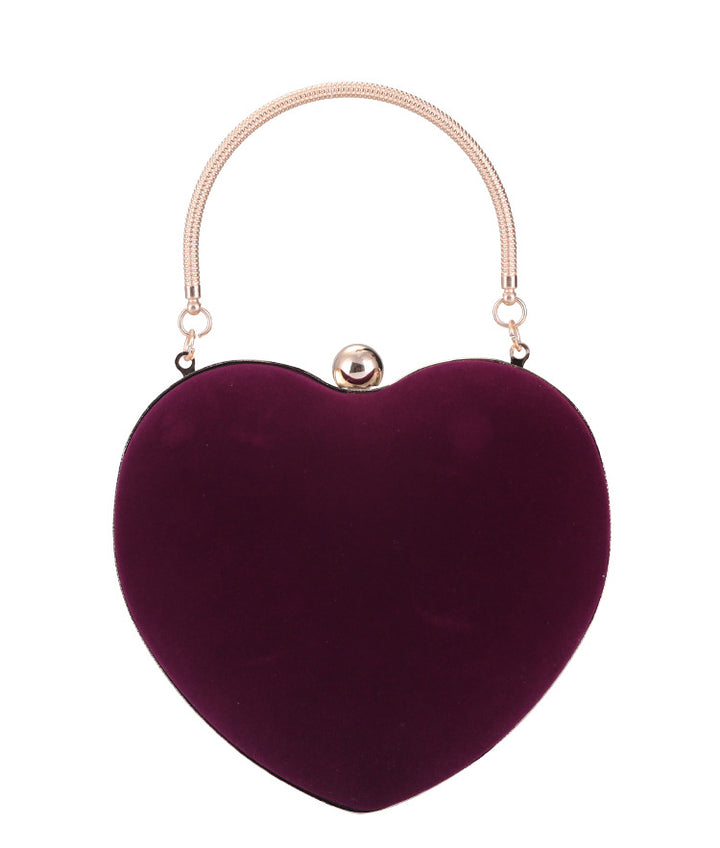 Heart-shaped purple handbag with a gold handle on a white background