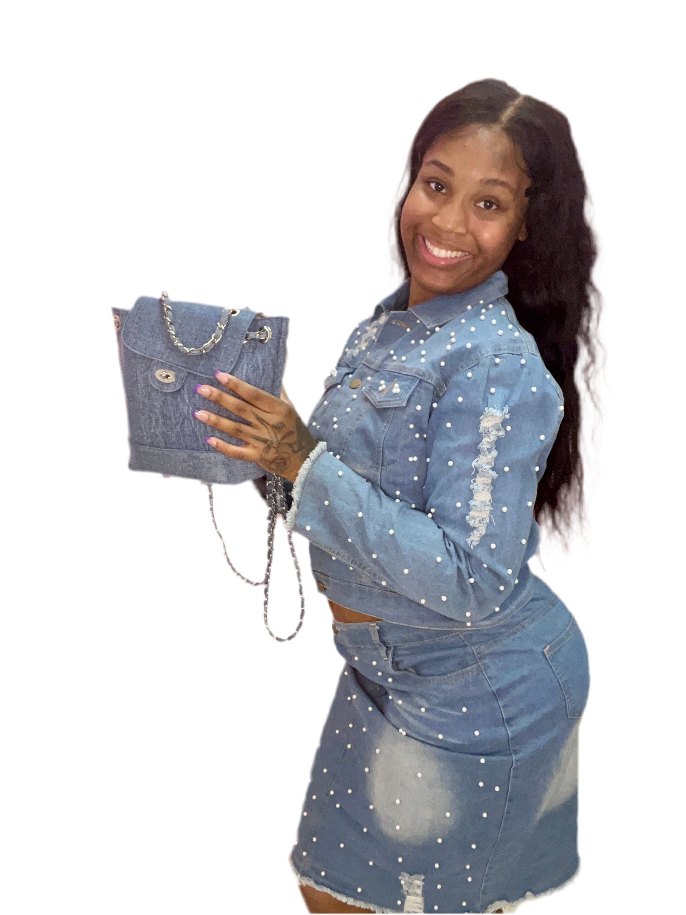 Woman wearing a denim outfit holding a matching denim handbag on a white background