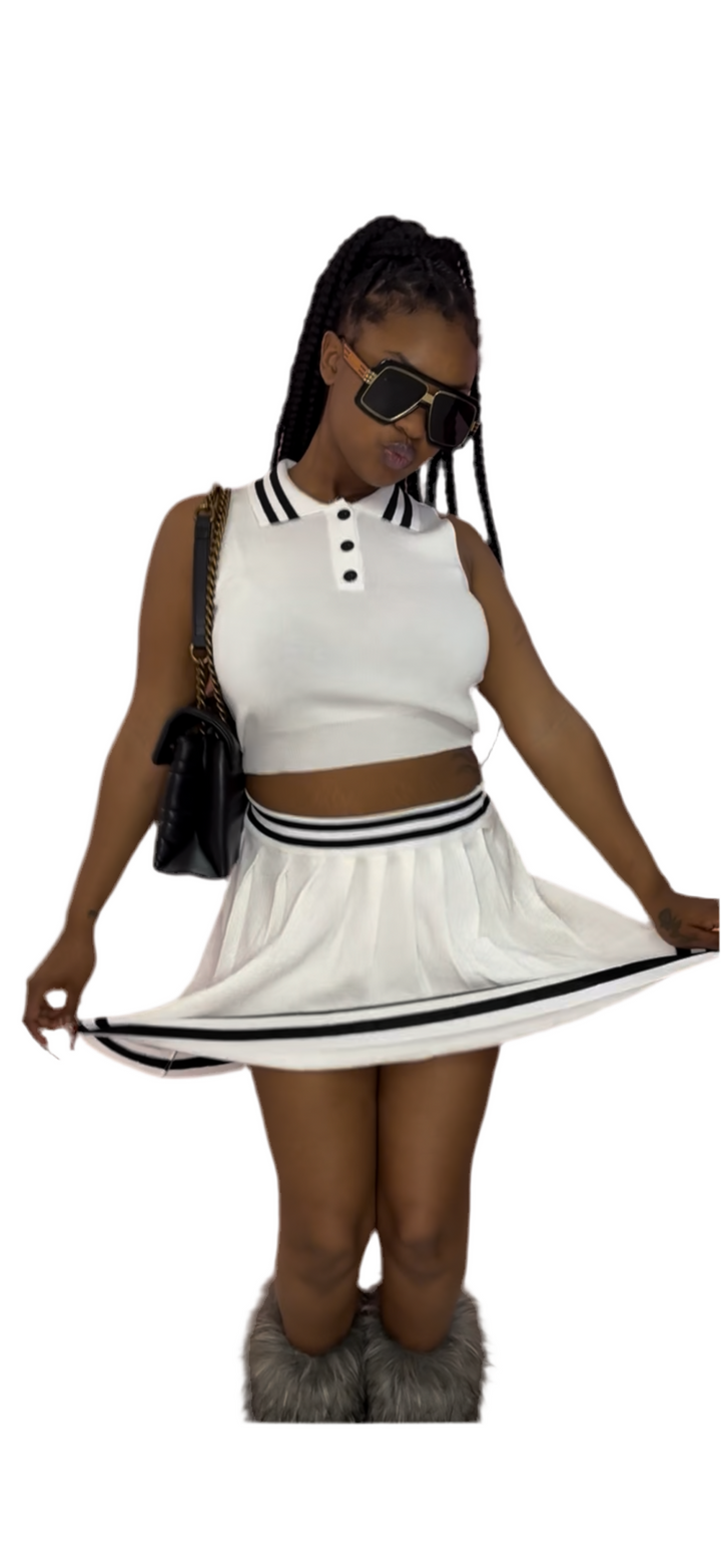 A woman wearing a white crop top and a matching ruffle skirt, with a handbag and high heels.